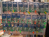 A retail display board filled with many packaged fishing lures. The cards are branded KINETIC and show various spinnerbites and topwater lures in different colors including green, orange, black, silver, and gold, hanging against a white display board.