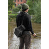 Angler standing on riverbank with fishing rod, wearing the Zebco Trophy Shoulder Sling Tackle Bag