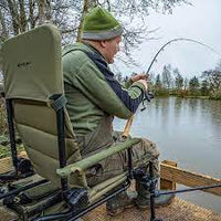 Angler fishing while sitting in Korum S23 Deluxe Accessory Chair